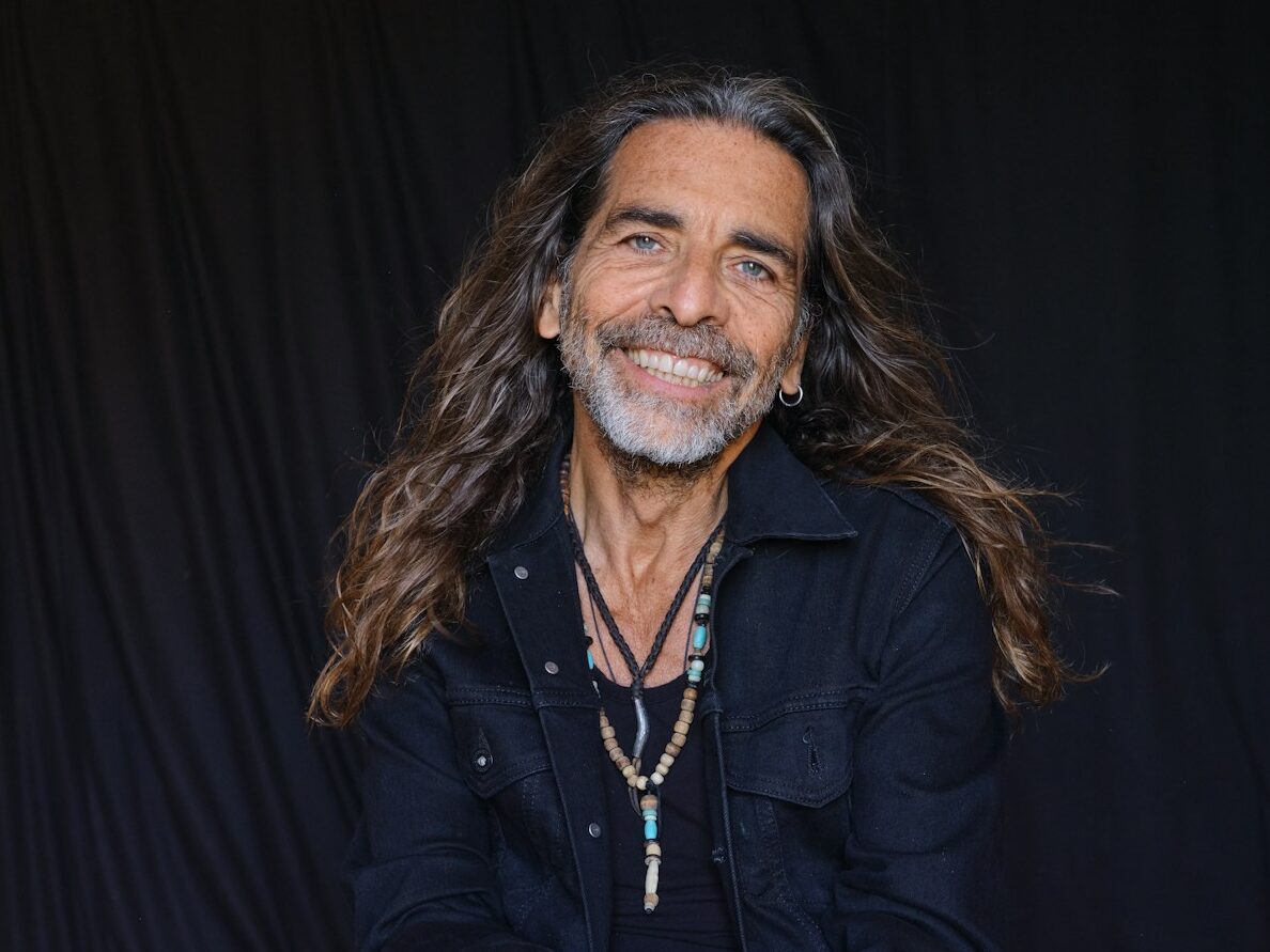 a man with long hair sitting on the ground