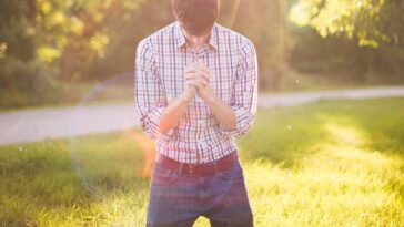 photo of man kneeling on grass near tree