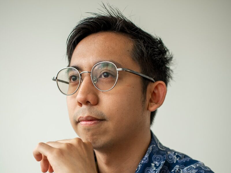 A man with glasses looks off to the side.