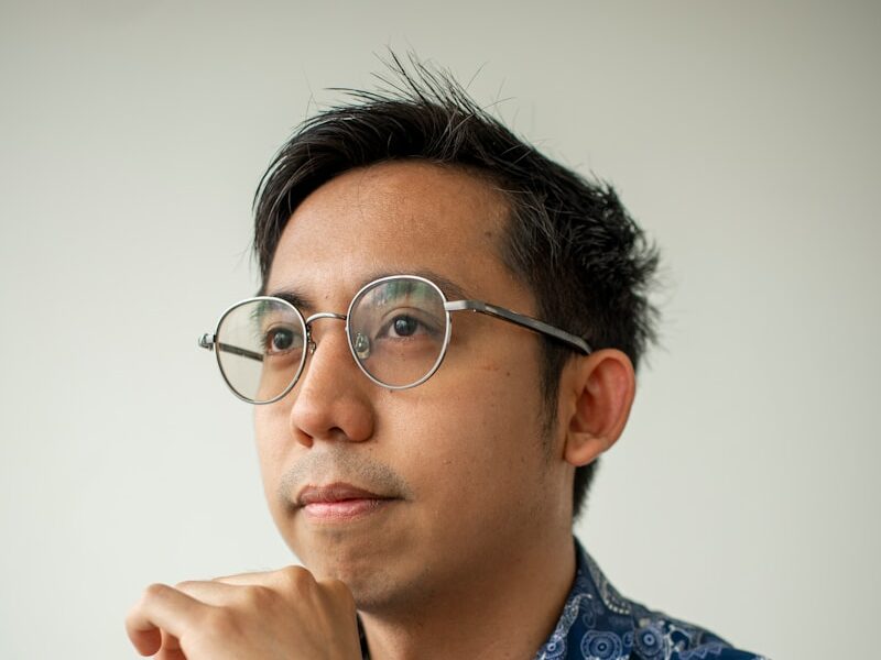 A man with glasses looks off to the side.