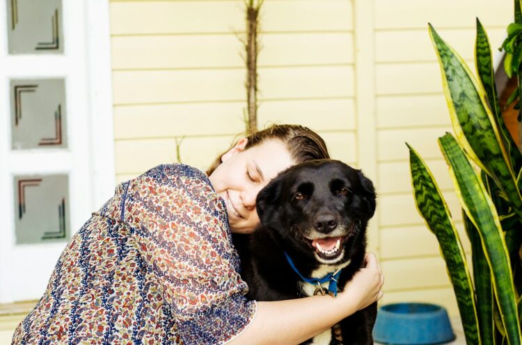 woman hugging black dog