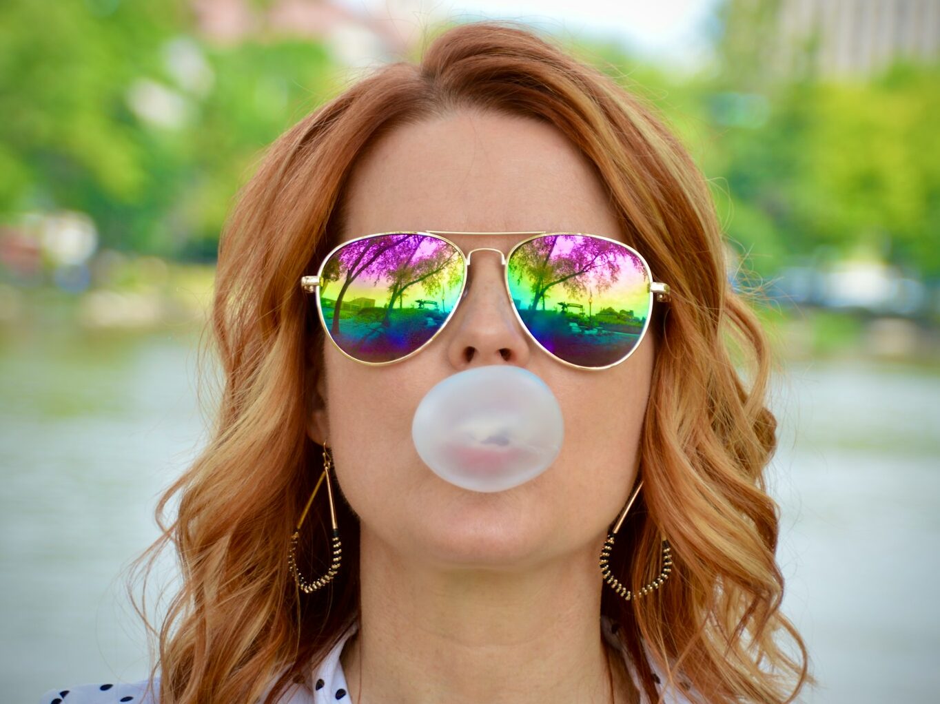 a woman wearing sunglasses blowing a bubble