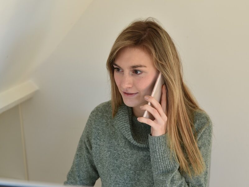 a woman sitting in front of a computer talking on a cell phone