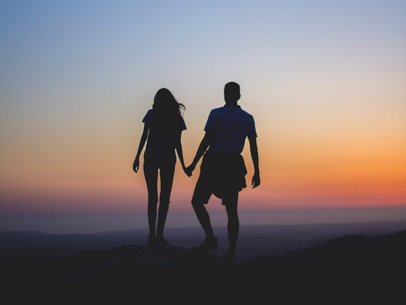 man and woman holding hands in silhouette photography