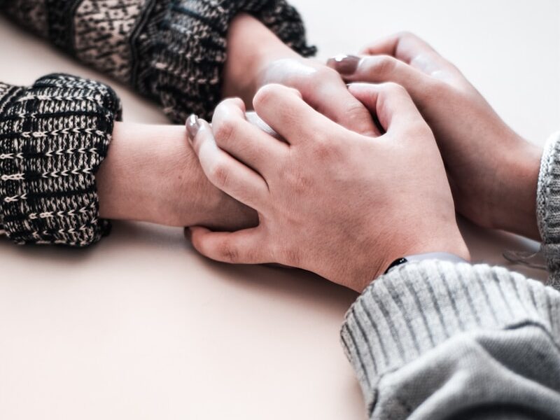person in gray long sleeve shirt holding persons hand