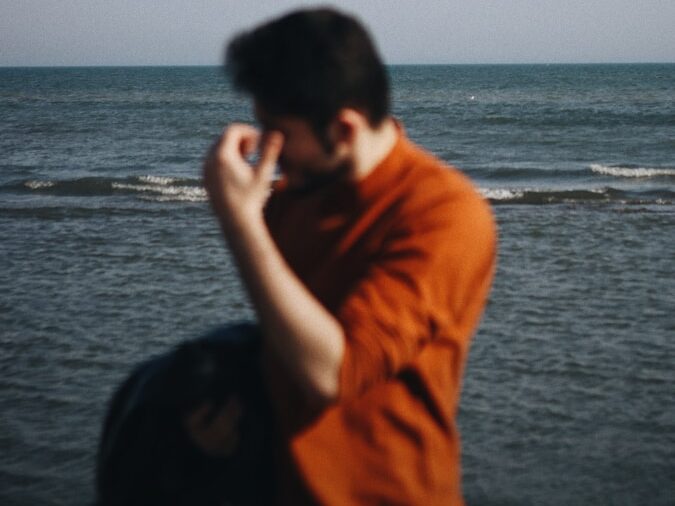 a man in an orange shirt on a cell phone