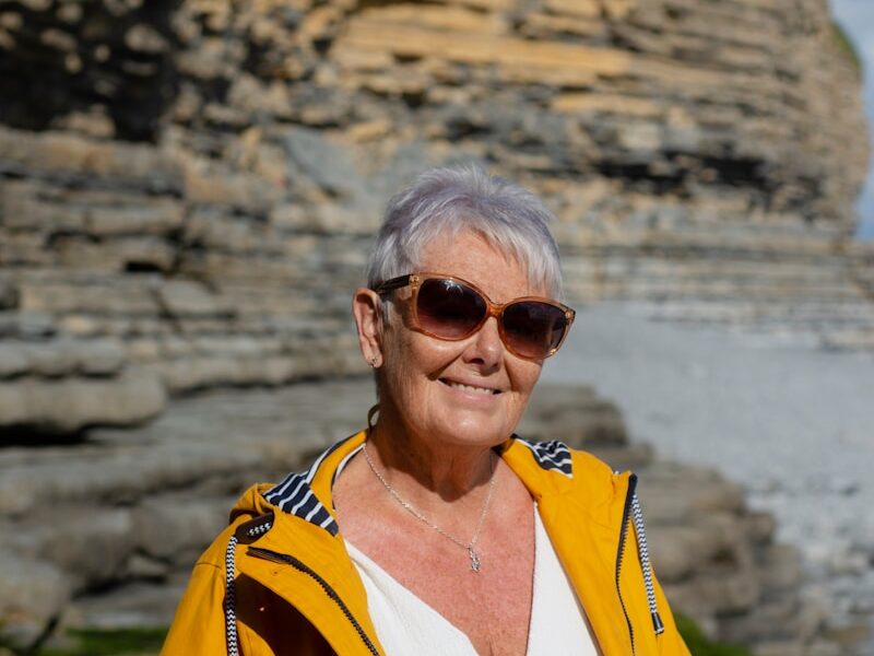 a woman wearing a yellow jacket and sunglasses