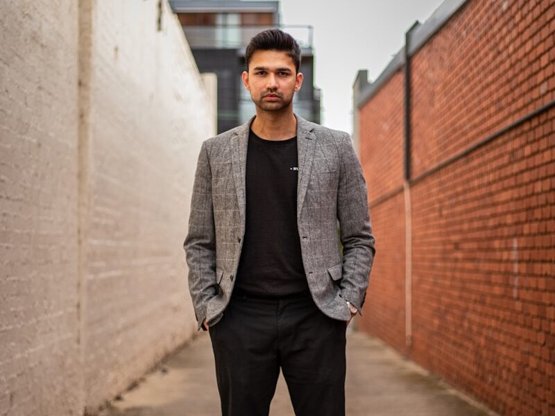 man in gray suit jacket and black pants standing on brown concrete pathway during daytime