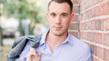 a young man leaning against a brick wall