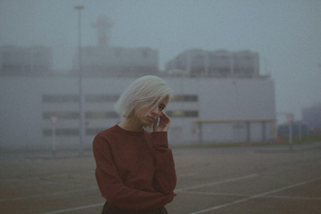 woman in red sweater standing on gray concrete floor during daytime
