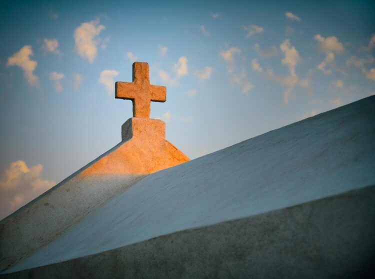 a cross on top of a building with a sky background
