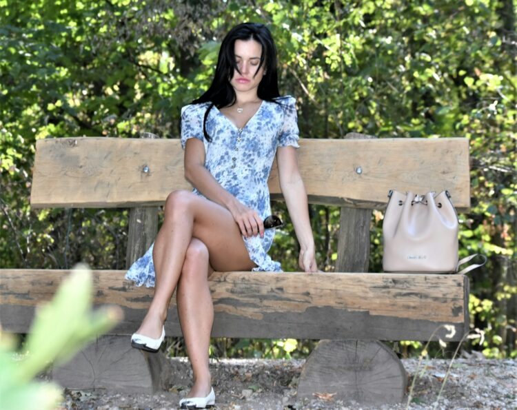 Woman in blue dress sitting on park bench