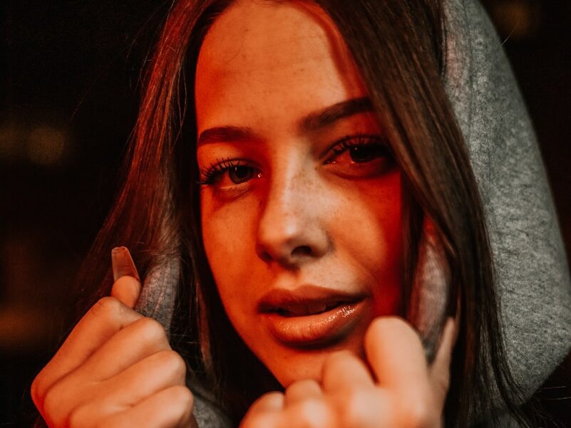 a woman in a hoodie holding a cell phone to her ear