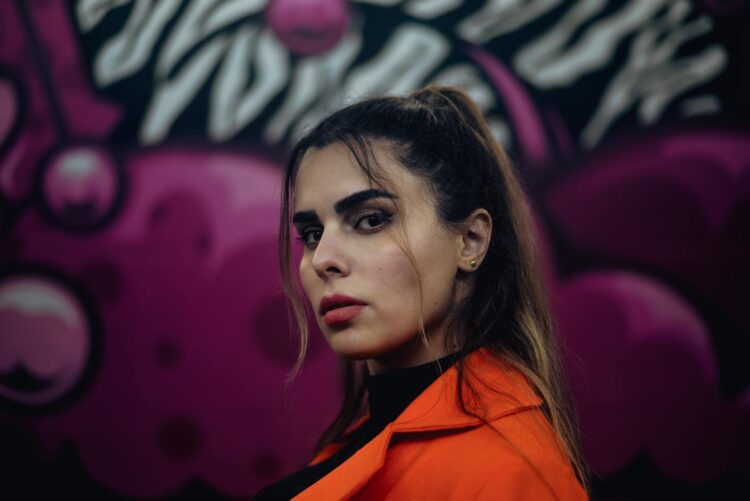 Portrait of a stylish woman posing against a vibrant street art background.