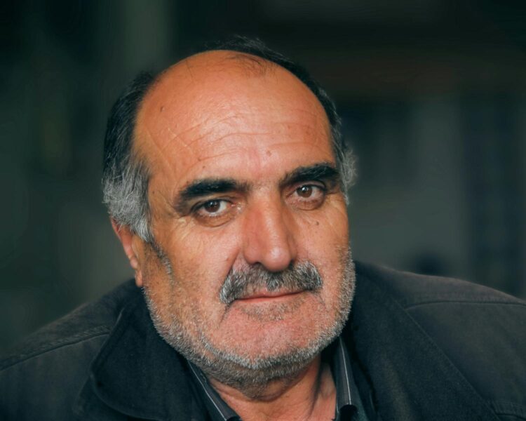 Close-up portrait of an elderly man with a mustache and facial hair, exuding wisdom.
