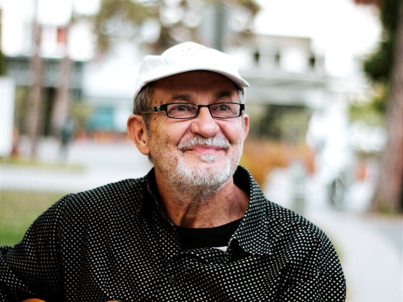 Smiling senior playing acoustic guitar in vibrant street scene, Hungary.