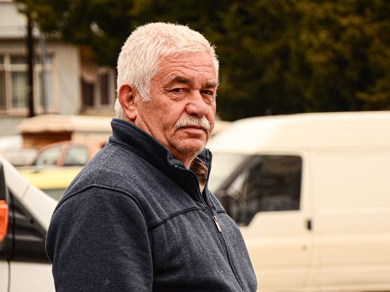 Portrait of a senior man with gray hair standing on a busy city street
