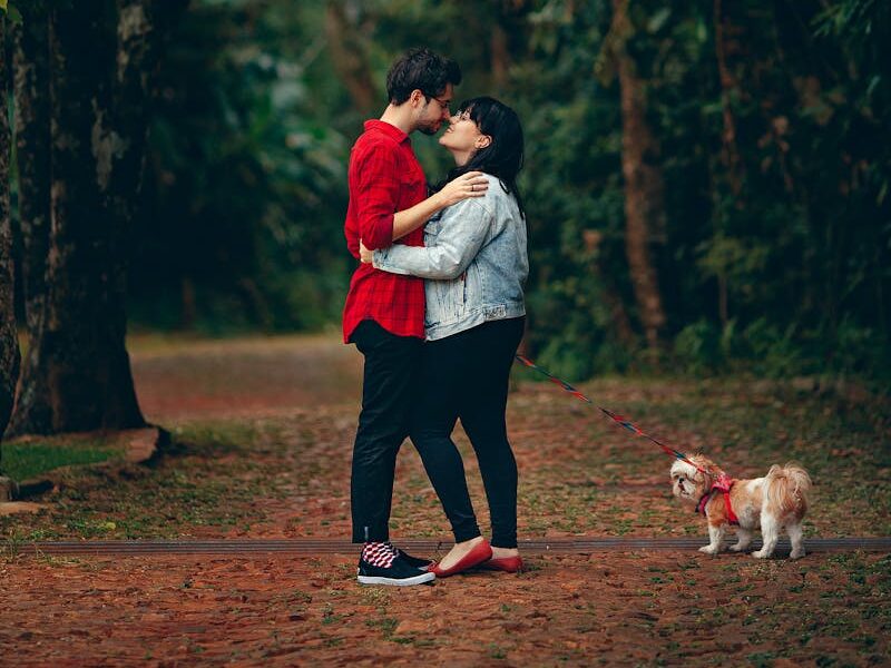 Young couple embracing in a lush forest with their small dog. A moment of affection and togetherness.