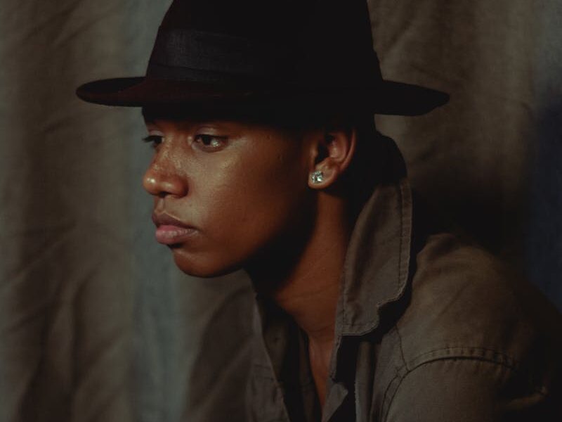 Elegant portrait of a man wearing a fedora, showcasing contemplative fashion style.
