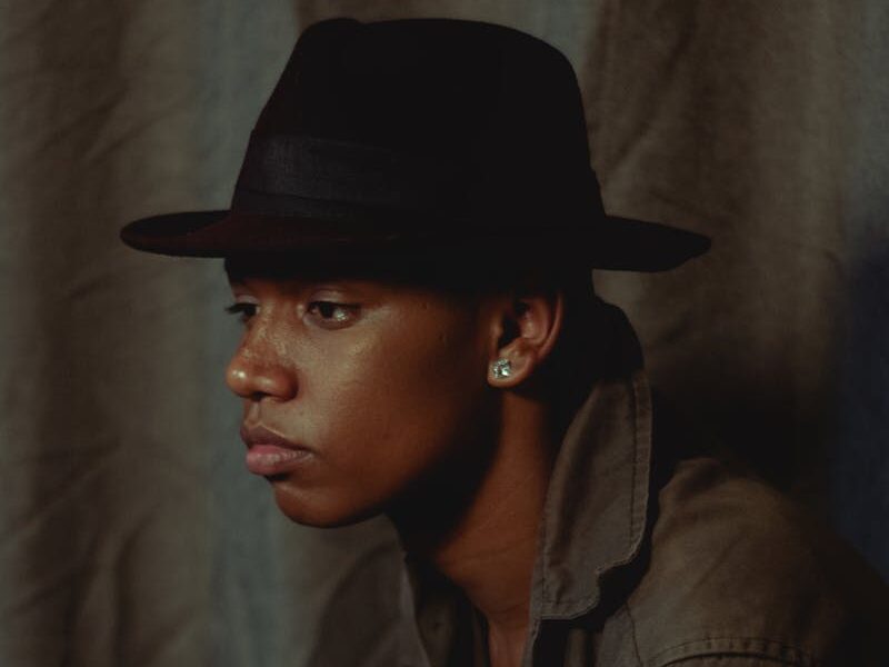 Elegant portrait of a man wearing a fedora, showcasing contemplative fashion style.