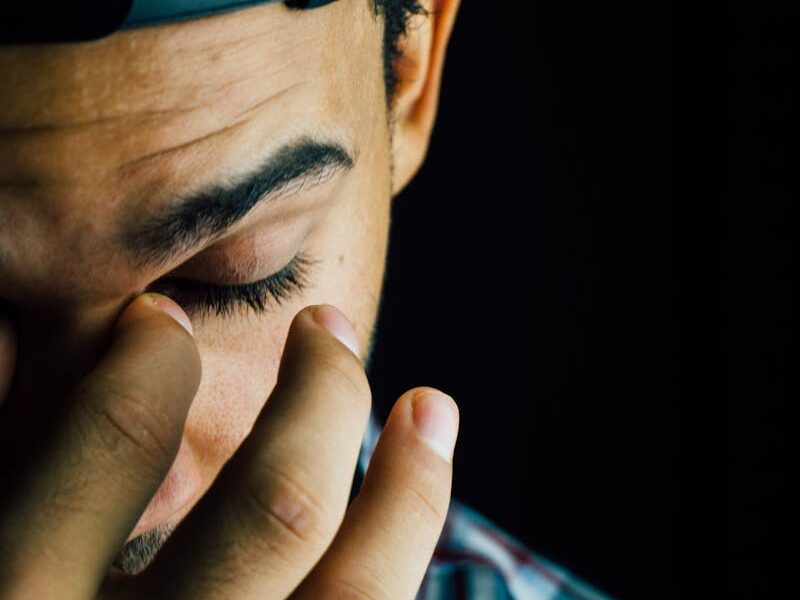 A close-up portrait capturing the emotional expression of a man in a dark studio setting.