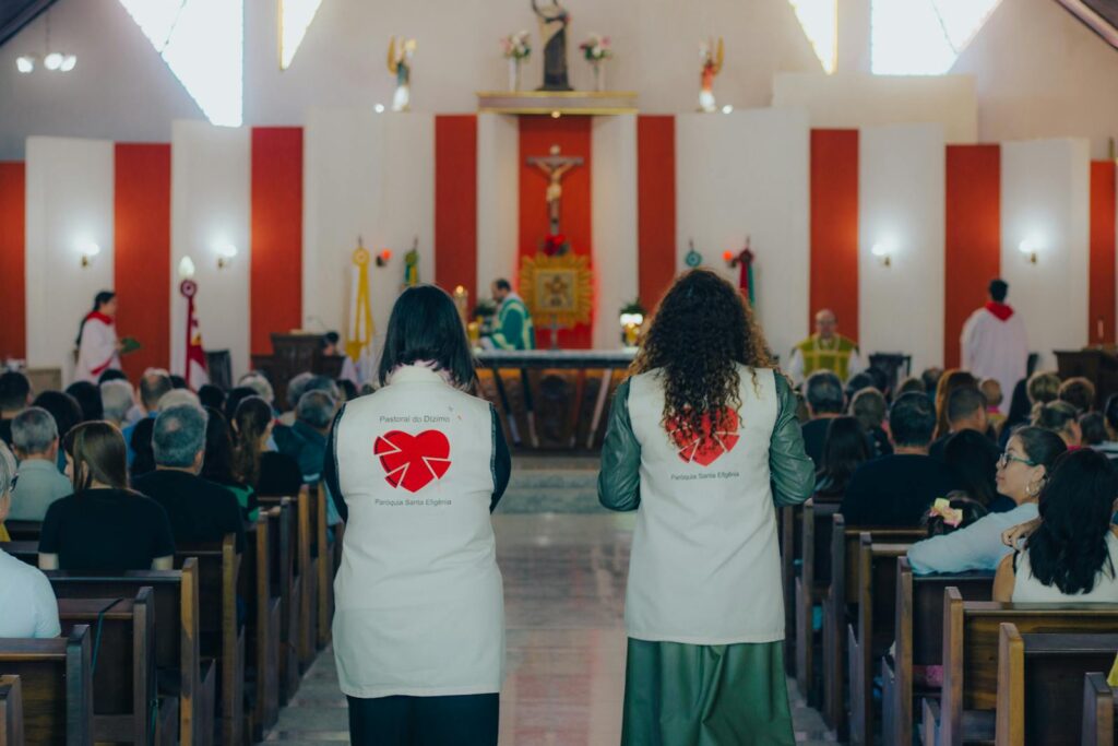 A congregation gathered for church mass with focus on two women assisting.