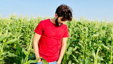 man in red crew neck t-shirt standing on green grass field during daytime