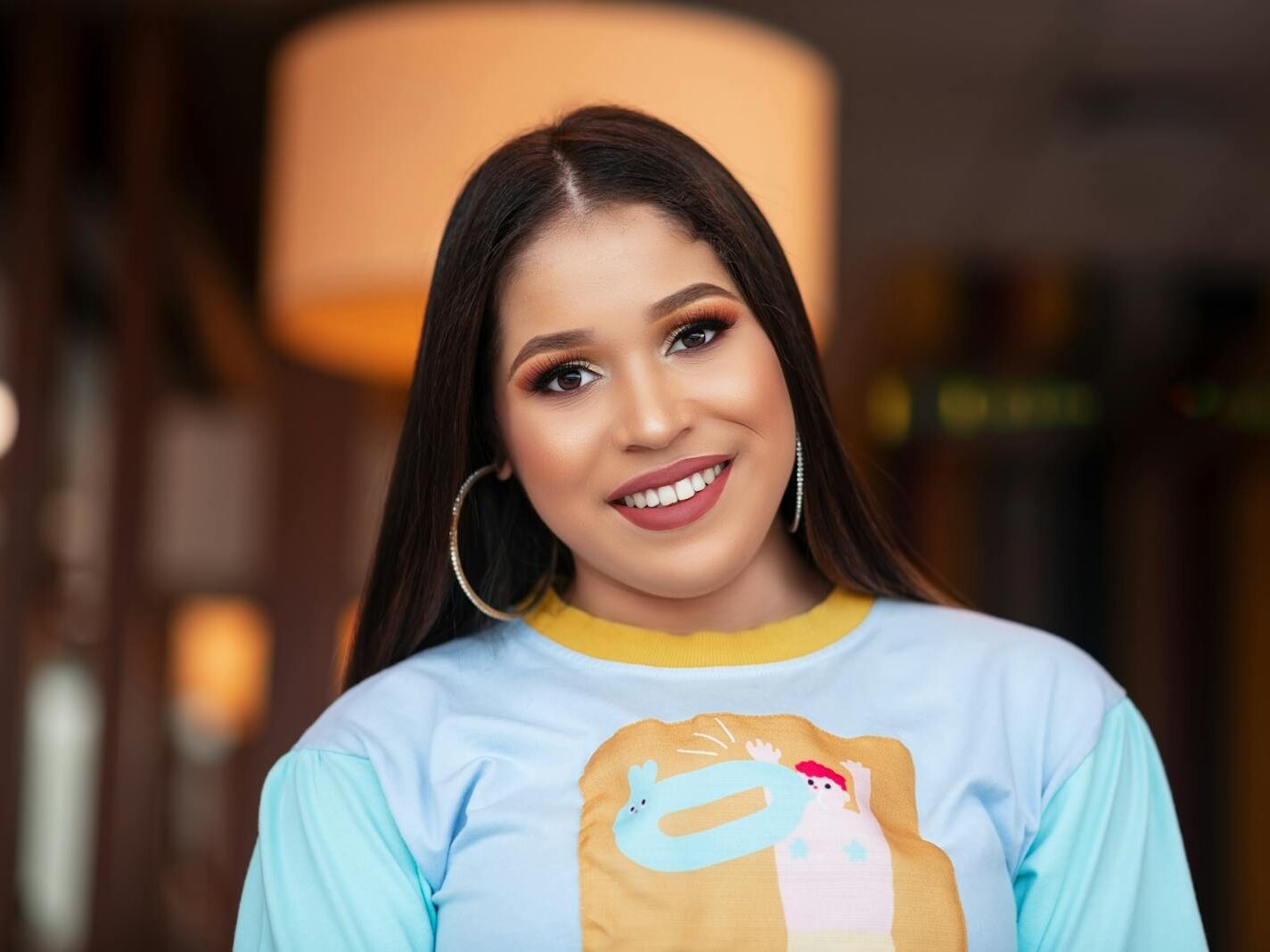 Portrait of a smiling woman indoors, showcasing happiness and style.
