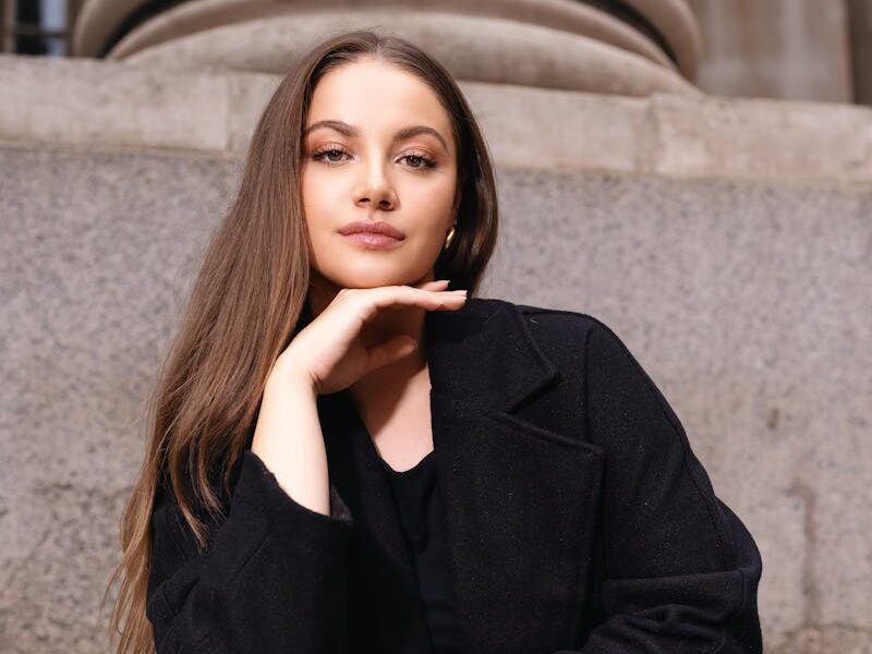 Elegant portrait of a confident woman sitting on steps in London, exuding style and grace.