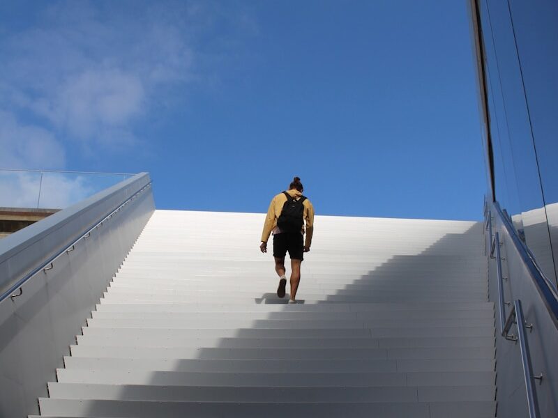 a man with a surfboard walking up a flight of stairs