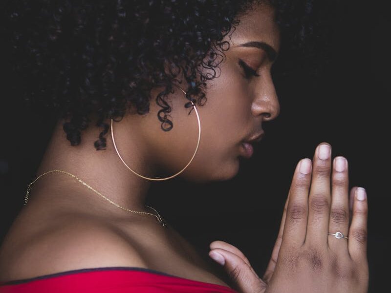 A serene profile of a woman praying in quiet contemplation, captured indoors.