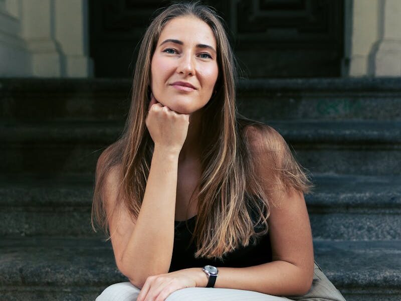 Portrait of a confident woman sitting on historical steps in Berlin.