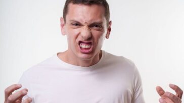 Angry young man clenching fists with a fierce expression. Studio portrait in Curitiba, Brazil.