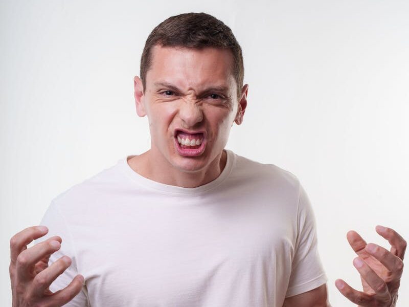 Angry young man clenching fists with a fierce expression. Studio portrait in Curitiba, Brazil.