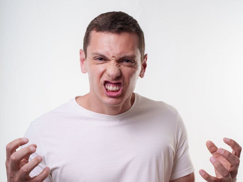 Angry young man clenching fists with a fierce expression. Studio portrait in Curitiba, Brazil.