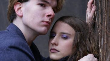 Intimate portrait of a couple embracing passionately against an urban wall.