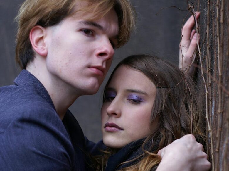 Intimate portrait of a couple embracing passionately against an urban wall.