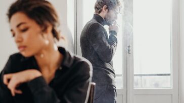 A couple experiencing tension and introspection indoors with a bright window.