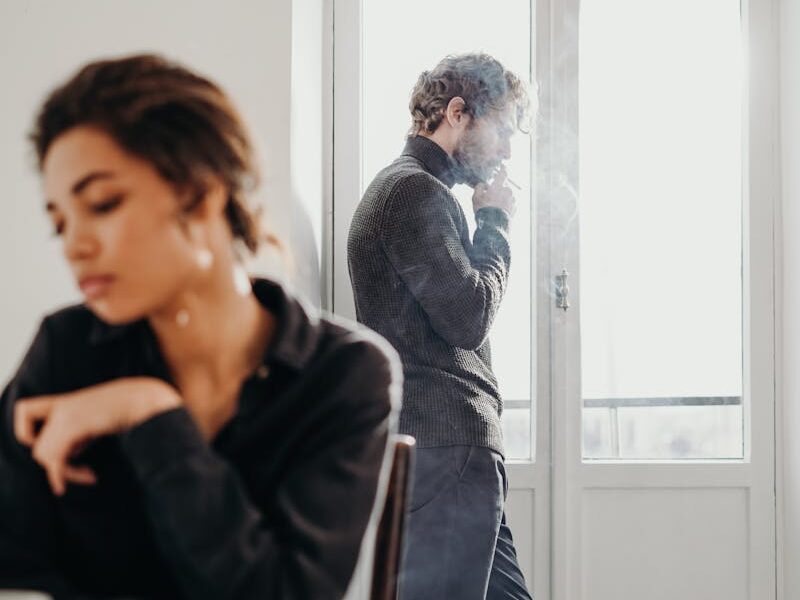 A couple experiencing tension and introspection indoors with a bright window.