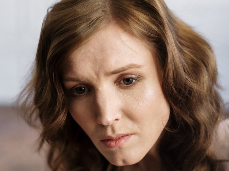 A woman with curly hair in deep thought, indoors, conveying emotion.