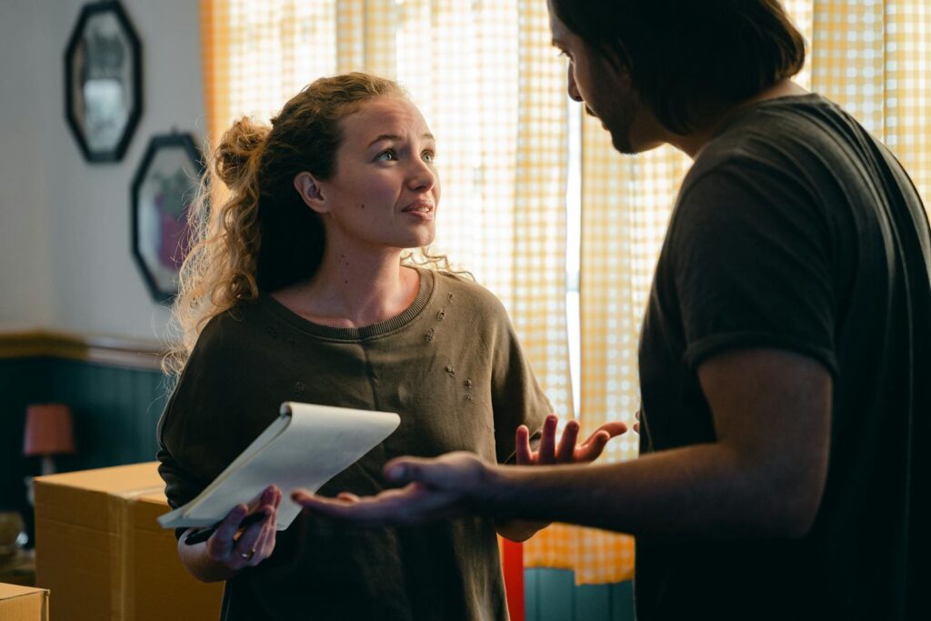 A couple talking in their living room surrounded by moving boxes, planning their new home setup.