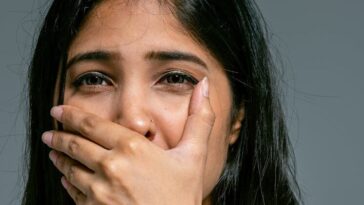 Emotional portrait of a woman covering her mouth in shock. Studio shot.