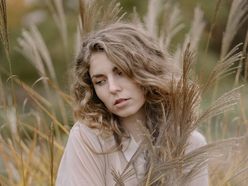 Thoughtful woman in wheat field, embracing autumn's beauty.