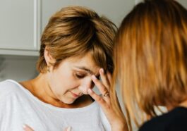 A tense moment between two women, one comforting the other indoors.