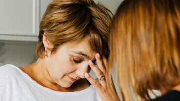 A tense moment between two women, one comforting the other indoors.