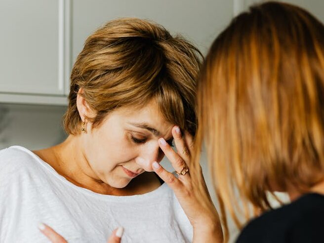 A tense moment between two women, one comforting the other indoors.