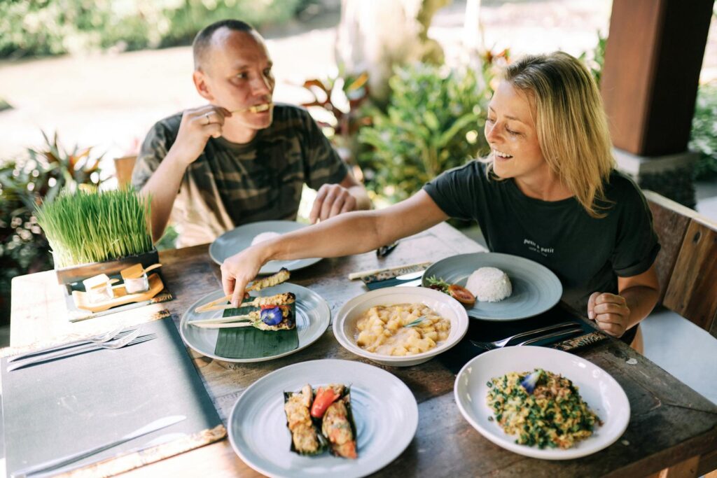 A couple enjoying a variety of Asian dishes outdoors at a cozy table setting.