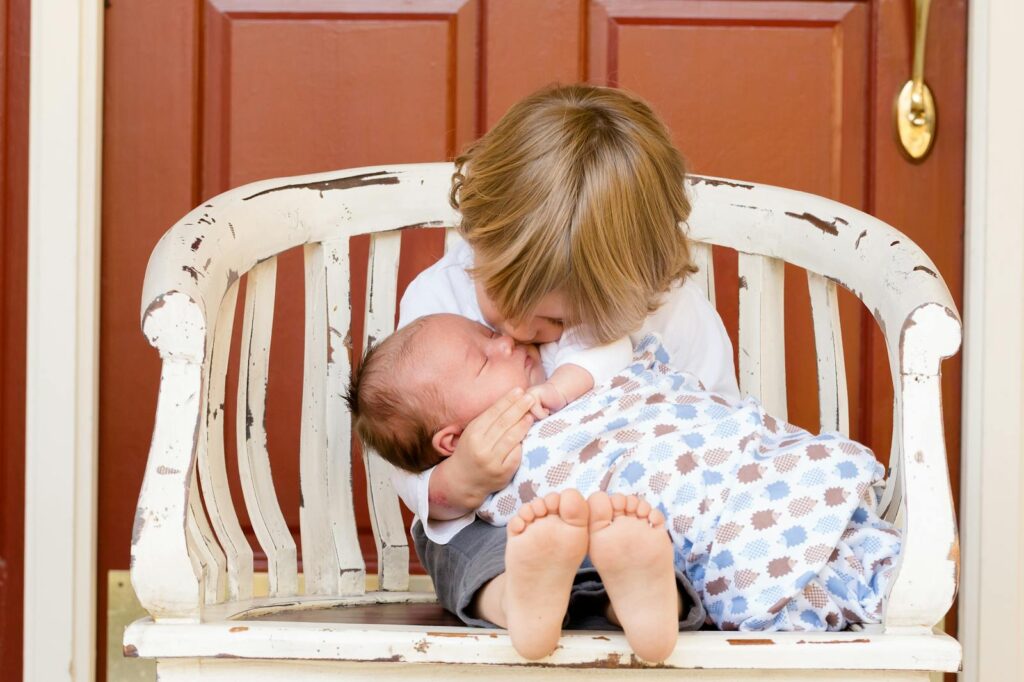A tender moment captured between an older sibling and newborn, embracing love and family bonds.