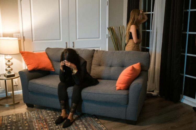 Two women experiencing emotional tension in a cozy living room setting.
