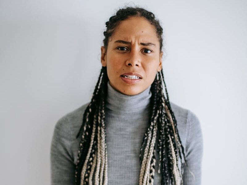 An adult black woman showing frustration and displeasure indoors with a gesture.